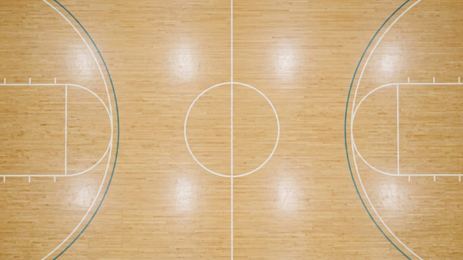 An overhead view of an indoor basketball court centred on the halfway line and centre circle, dividing the floor into two symmetrical halves